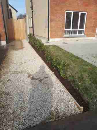 Image of the front garden with lawn removed and decorative gravel with timber edging and bark mulch beneath the hedge.