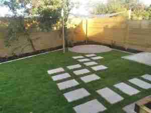 New granite sett circular patio , shade sail with stepping stones and timber clad wall