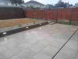 Image of Porcelain patio with retaining wall and gravel ground cover to replace grass