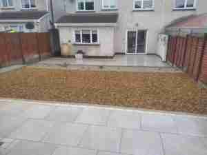 Porcelain patio with retaining wall and gravel ground cover to replace grass